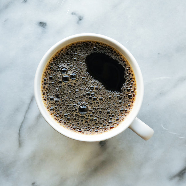 White coffee mug with black coffee on marble counter